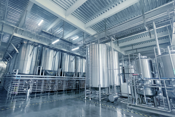 Large stainless steel storage and process tanks with platforms and piping inside a bright, clean modern industrial facility